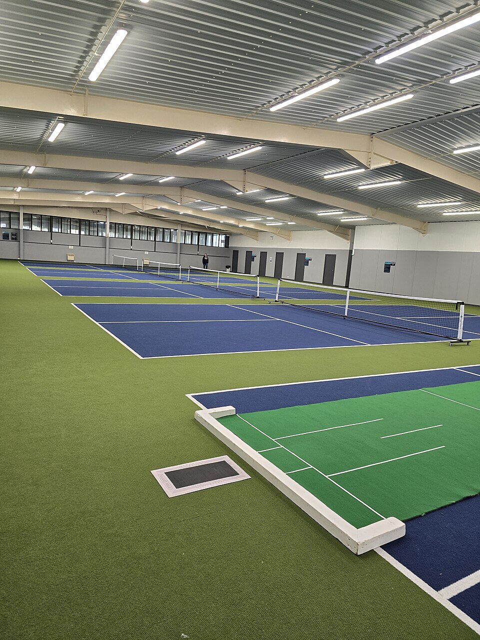 Indoor pickleball court with bright overhead lighting